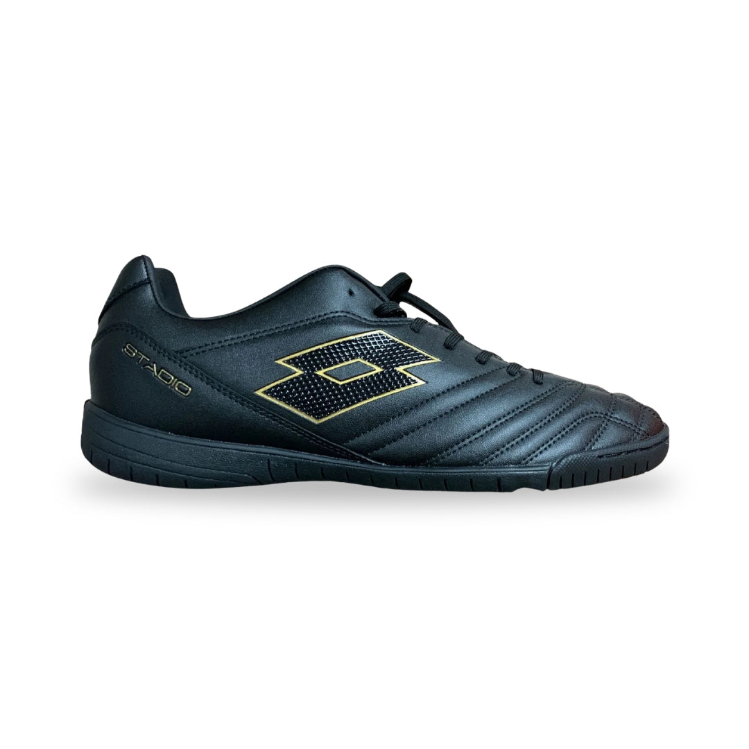 A black indoor soccer shoe with gold accents, featuring a textured geometric logo on the side and the brand name 'STADIO' printed near the heel, shown against a plain white background.