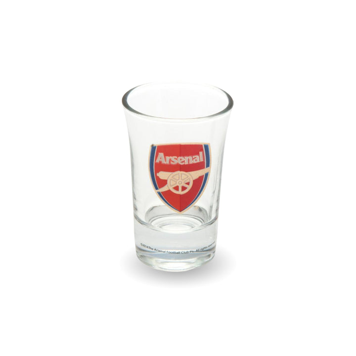 A clear glass Arsenal shot glass featuring the club's red and gold crest on the front, set against a plain white background.