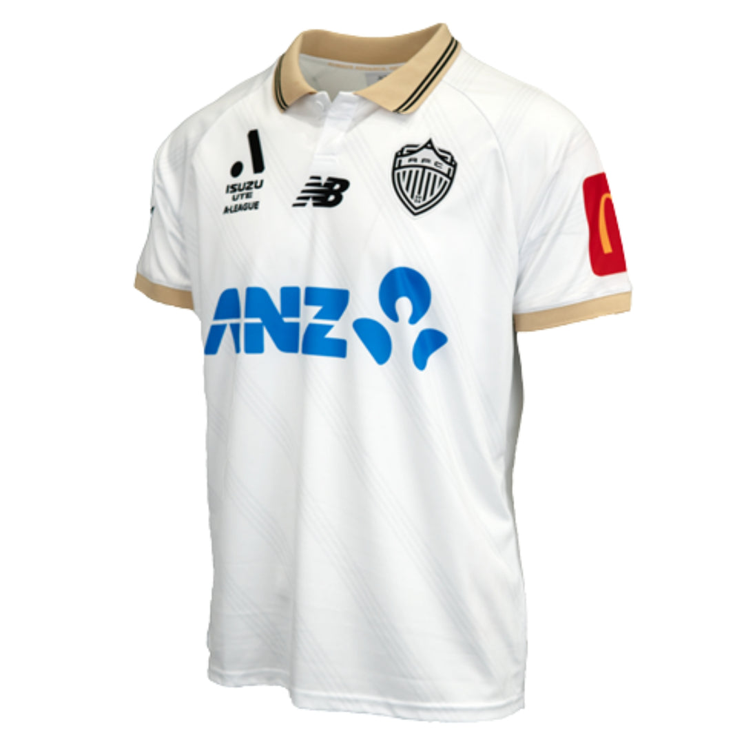 A white soccer jersey with gold trim on the collar and sleeve cuffs, featuring the ANZ logo in blue across the chest, the New Balance logo, and the Club Auckland crest. A red sleeve patch is visible on the right sleeve.
