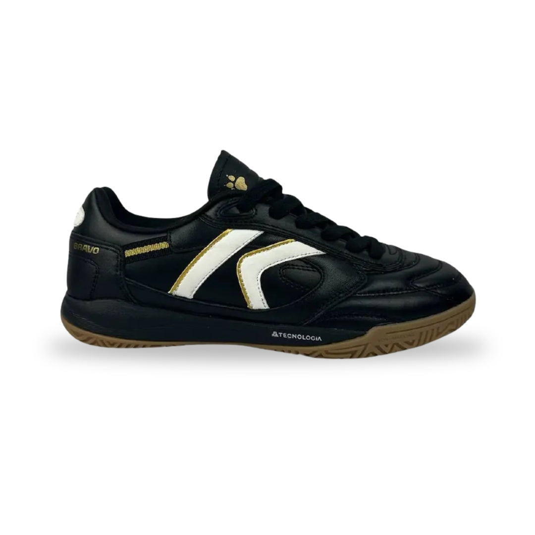 A black leather indoor soccer shoe with a white and gold side stripe, black laces, and a brown gum sole, shown against a plain white background.