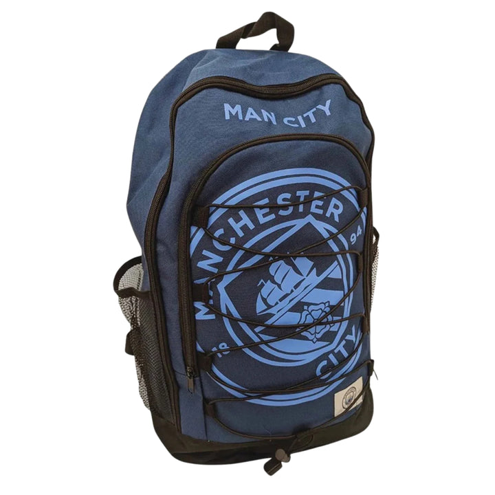 A blue Manchester City backpack with the club's crest printed on the front pocket, black bungee cords across the pocket, and 'MAN CITY' text above it, shown on a plain white background.