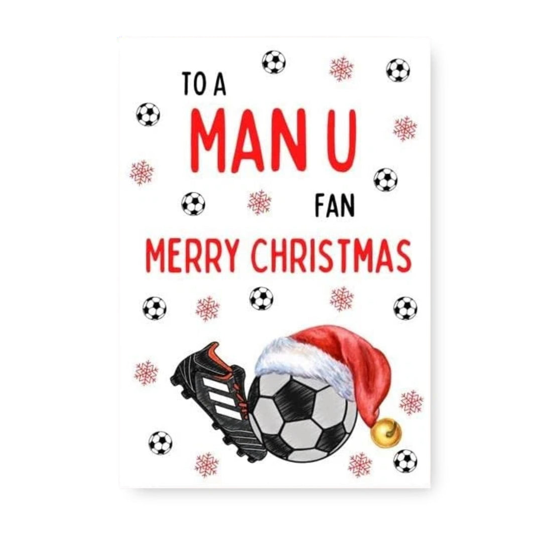 A Christmas-themed greeting card or print with the text 'TO A MAN U FAN MERRY CHRISTMAS' in red and black lettering on a white background. The design includes soccer balls, snowflakes, a soccer cleat, a soccer ball, and a Santa hat with a gold bell.