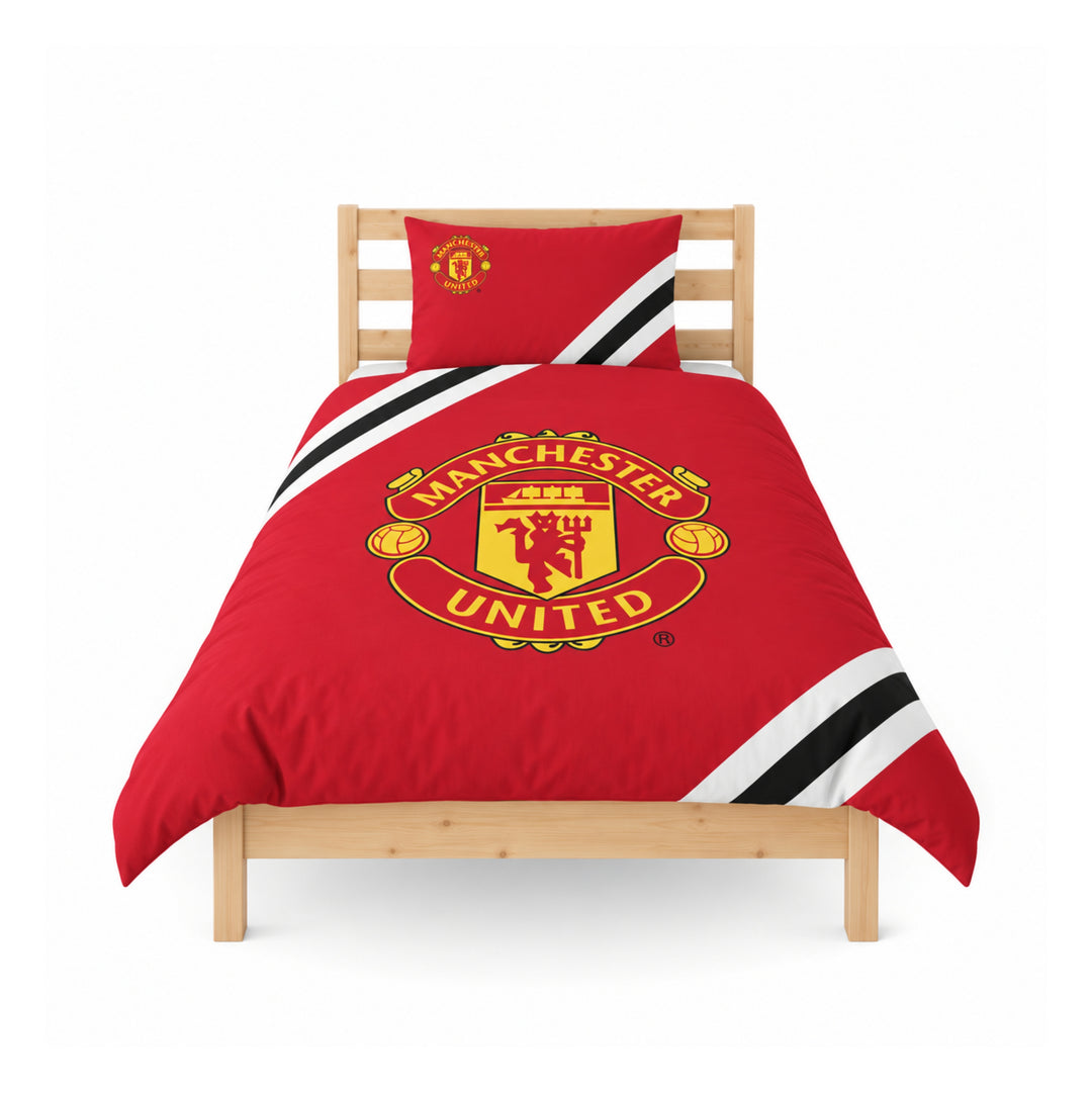 A single bed styled with a red Manchester United-themed bedding set, including a duvet cover and matching pillowcase, featuring the club's crest and black-and-white striped accents, shown on a light wood bed frame against a white background.