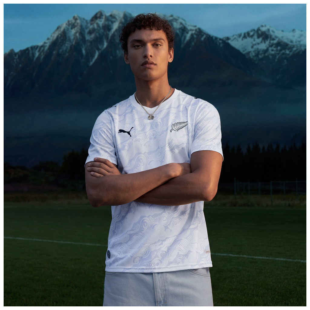 Person wearing NZ All Whites shirt with NZ mountains in background