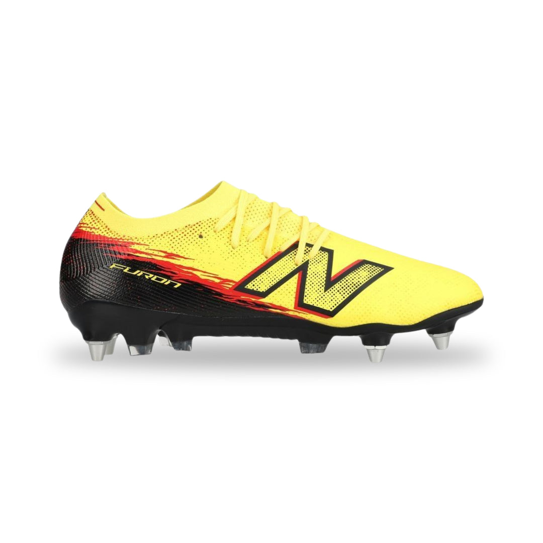 A New Balance soccer cleat in bright yellow with a black heel and a red and black flame graphic behind the large 'N' logo, on a white background.