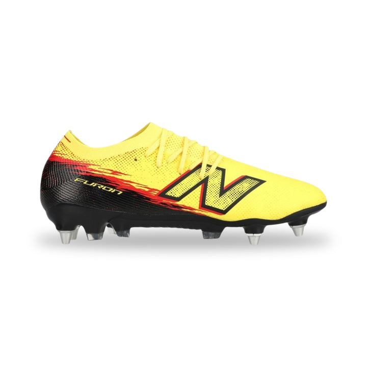 A New Balance soccer cleat in bright yellow with a black heel and a red and black flame graphic behind the large 'N' logo, on a white background.