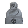 Gray beanie with pom-pom and Manchester United logo on a white background