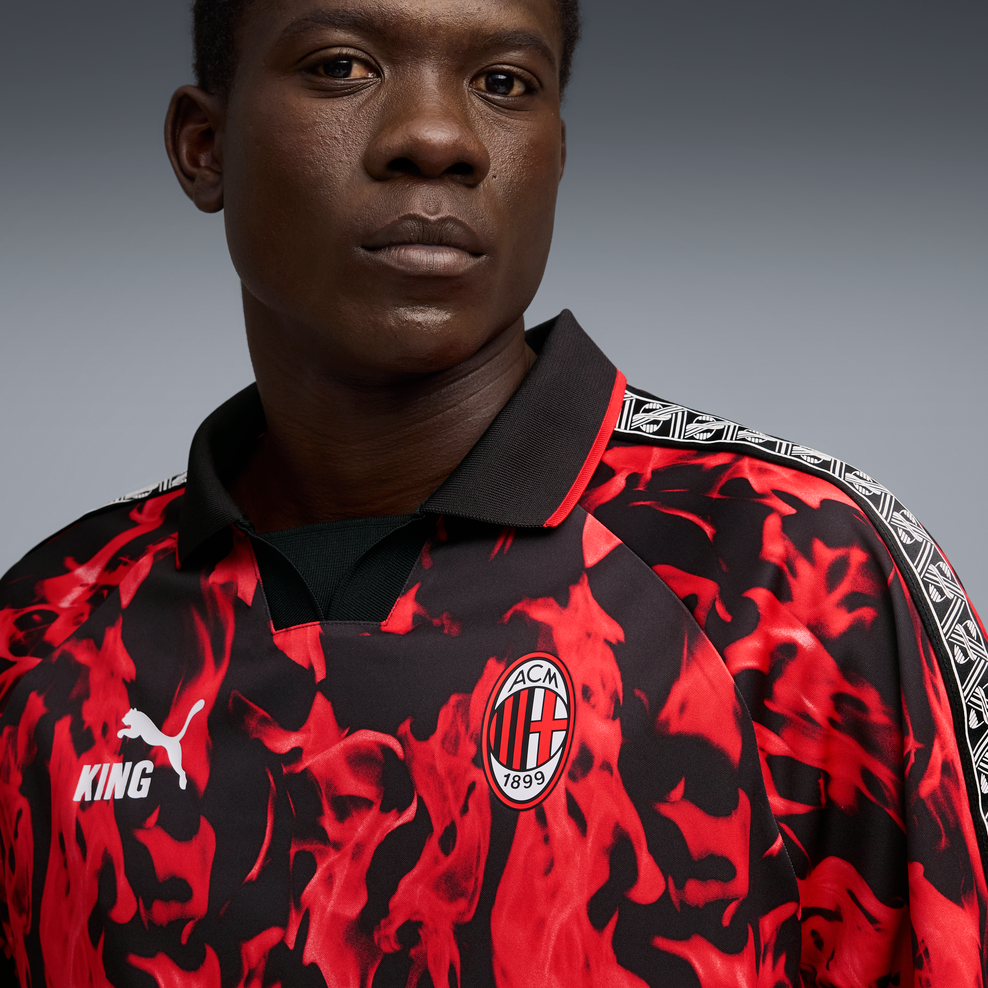 Person wearing a red and black patterned sports jersey with a logo on a gray background