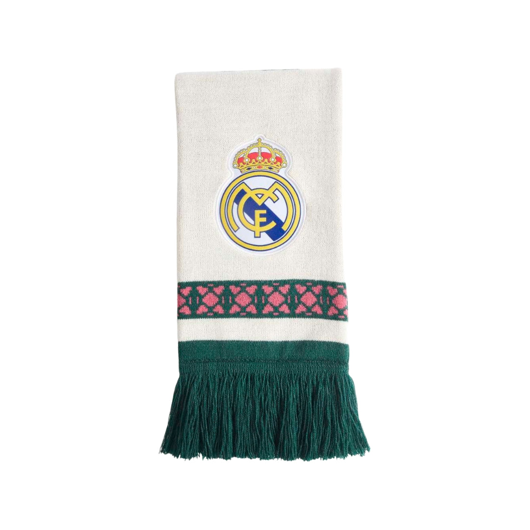 A Real Madrid knit scarf in off-white with the club's crest embroidered in the center, a pink and green patterned band, and a dark green fringed bottom, shown on a plain white background.